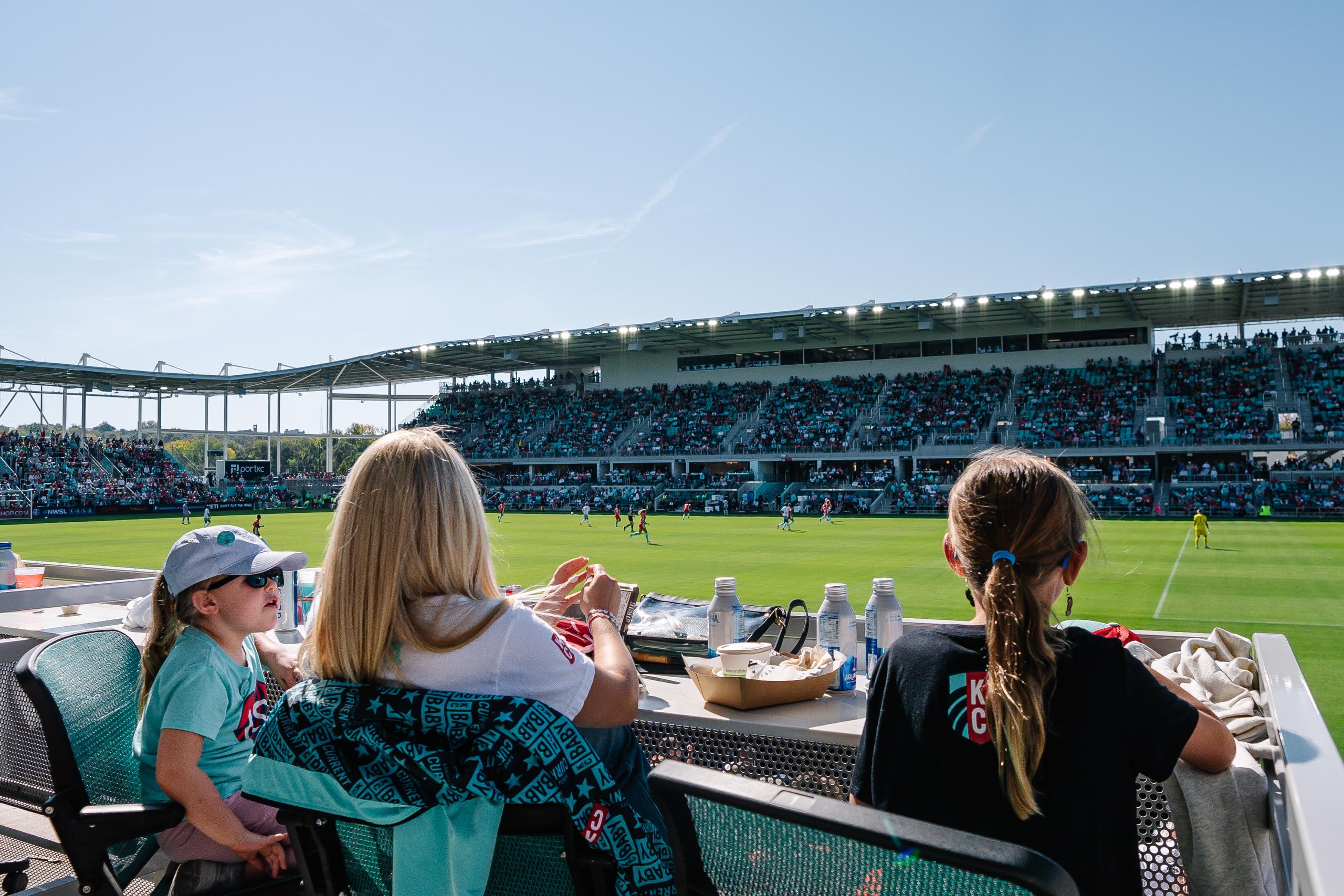 An image of three fans seated in the east loge box as the watch the match.