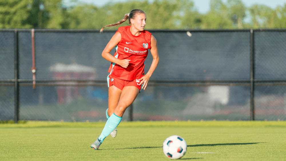 A cover image of Avery Clark dribbling the soccer ball for KC Current II.