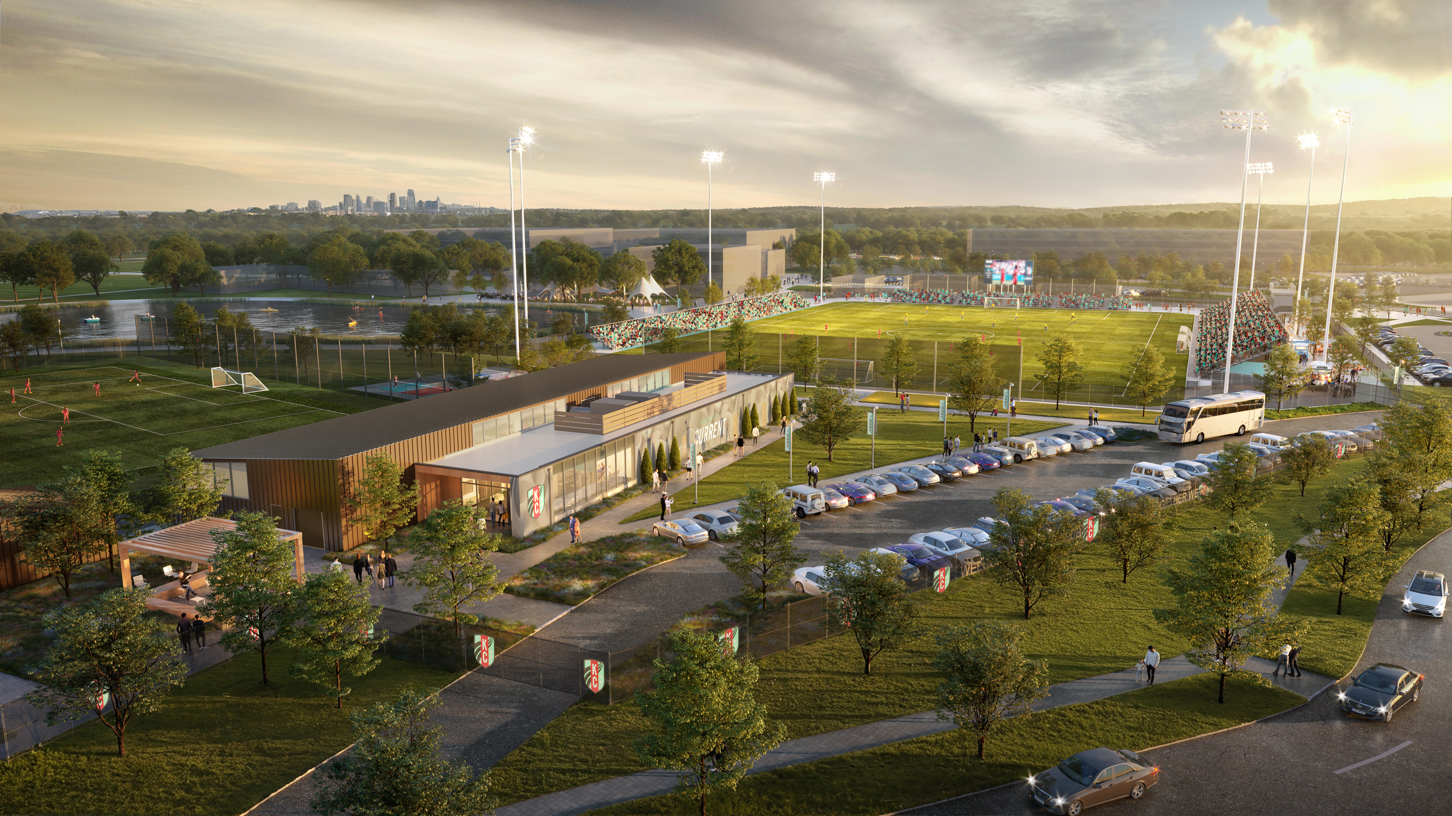 A soccer field in a small soccer stadium with cars parked around it.